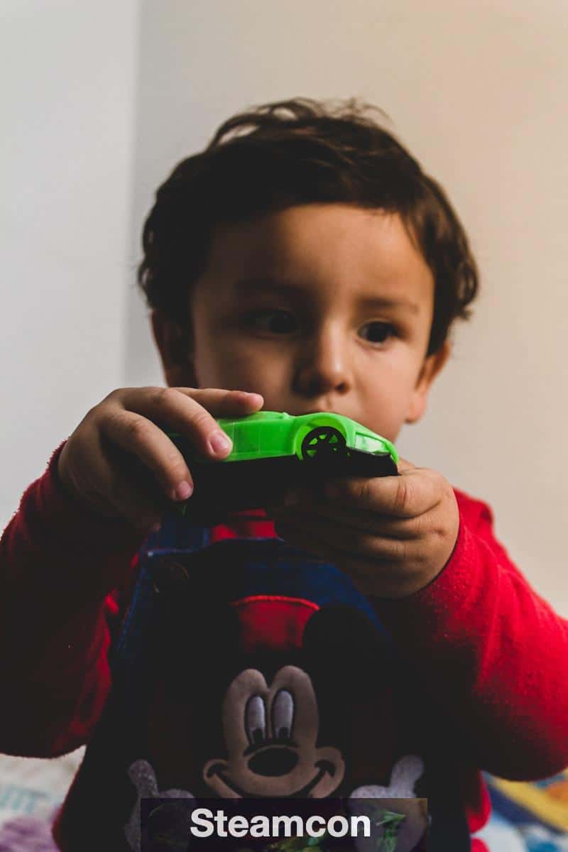 boy in red and black long sleeve shirt holding green plastic toy gun