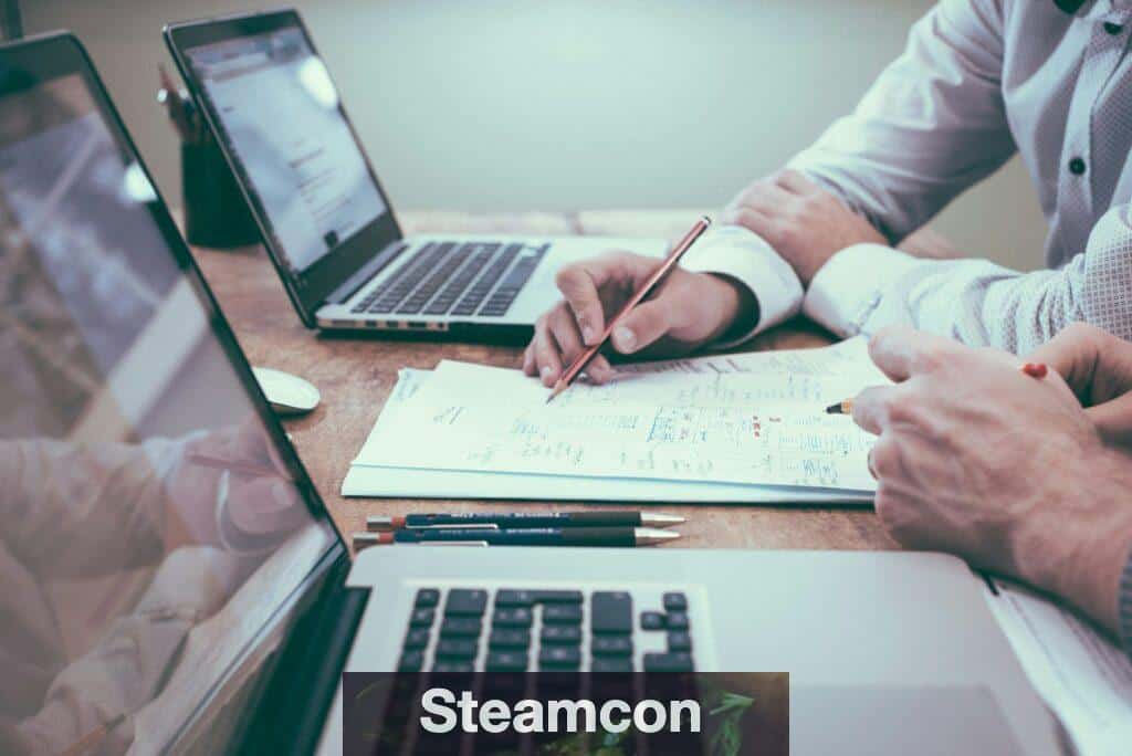 person holding pencil near laptop computer