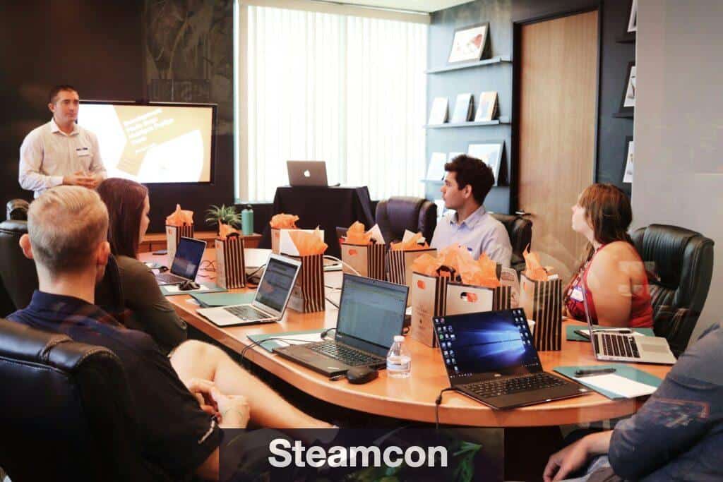 man standing in front of people sitting beside table with laptop computers